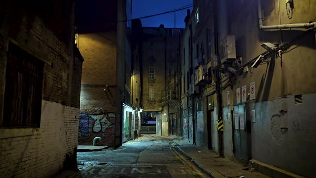 a scary and empty alleyway in Dublin city's center during nigh time with graffitis in the brick walls - old UK and Irish architecture - Dublin Ireland