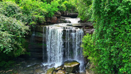 A breathtaking waterfall nestled in a vibrant jungle, captured from a bird's eye view, reveals a...