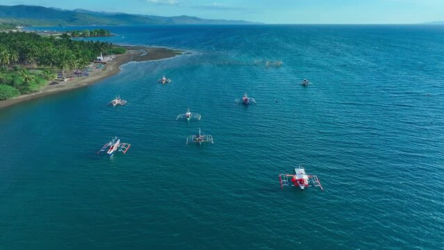 Aerial drone flight over coastline of Sarangani with beach and traditional bangka, fishing boats in south Philippines. Birds eye shot in summer season.