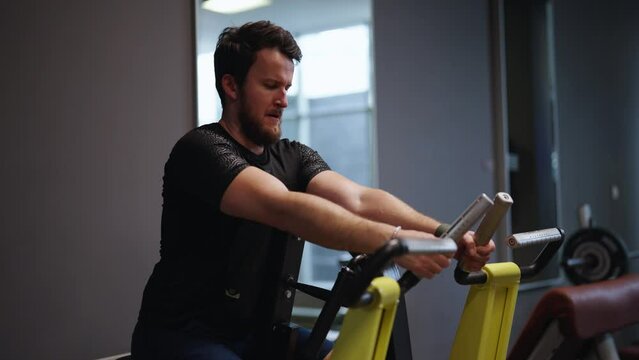 Strong male at gym perform seated back exercise with leverage low row machine