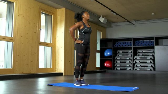 Standing in a split stance, one leg in front, and slowly moving forward in one bended knee on each side as the woman dips in lunges for her exercise.