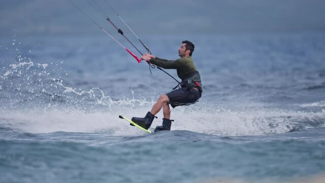 Kiteboarder pumps and pulls into spin midair leaning back and riding on water