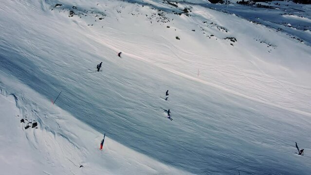 People skiing on white mountain slope in Alps, aerial