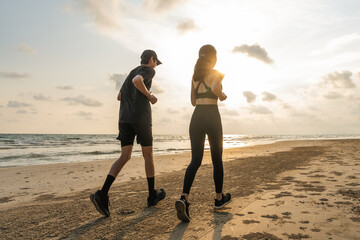 Asian Couple jogging and running outdoors sea sand beach. Sporty people wearing sportswear jogging....