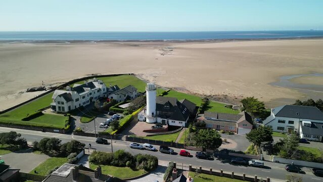 Converted lighthouse, Hoylake Beachfront on a sunny afternoon - aerial drone orbit revealing beautiful scenery, Wirral, UK