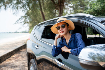 A young beautiful asian woman travel to the sea by car on a bright day. With beautiful blue sky. Vacation holiday weekend after hard work. Sticking her head outta the windshield