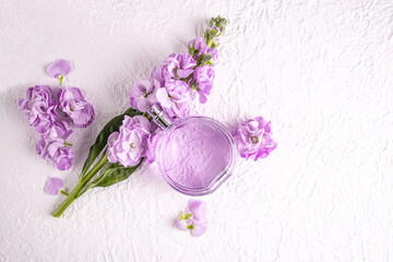 A chic round bottle with a delicate floral fragrance lies on a beautiful lilac flower. Top view....