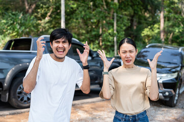 Obraz premium Asian man and woman drivers arguing after traffic collision accident feeling serious and stressed. Parked on side way road Call Emergency assistance or insurance claim service. Car Crash