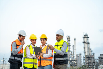 Group of Asian engineer people with safety helmet standing front of oil refinery. Industry zone gas...