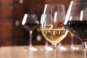 Tasty red and white wines in glasses against blurred background, space for text