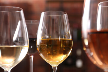 Different tasty wines in glasses against blurred background