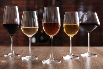 Different tasty wines in glasses on wooden table