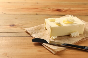 Tasty butter and knife on wooden table. Space for text