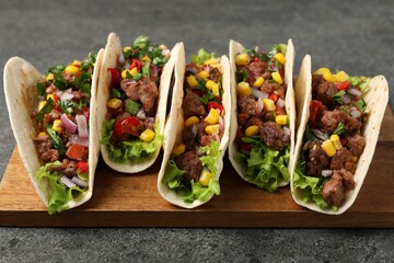 Delicious tacos with meat and vegetables on gray textured table