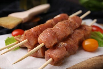 Skewers with cut raw marinated meat on wooden table, closeup
