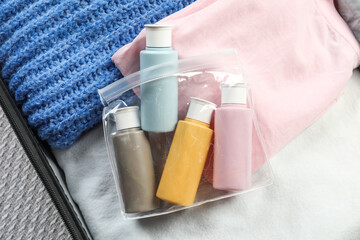 Plastic bag of cosmetic travel kit in suitcase, top view