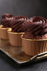 Delicious chocolate cupcakes on black textured table, closeup