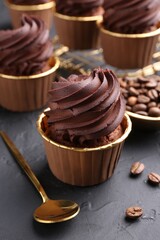 Delicious chocolate cupcakes and coffee beans on black textured table
