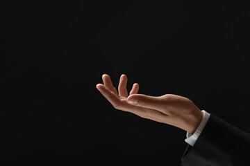 Man holding something in hand on black background, closeup. Space for text