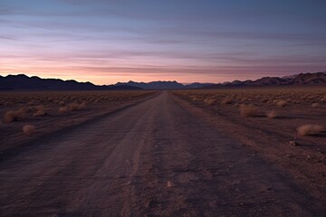 Fototapeta premium Desert road at dusk with distant city lights on the horizon.