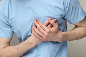 Man suffering from heart hurt on grey background, closeup