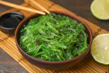 Tasty seaweed salad in bowl served on wooden table, closeup