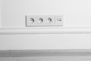 Electric power sockets on white wall indoors