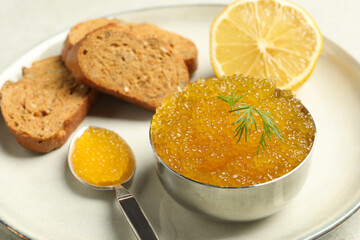 Fresh pike caviar in bowl, lemon and bread on light table, closeup