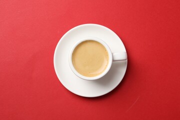 Aromatic coffee in cup on red background, top view
