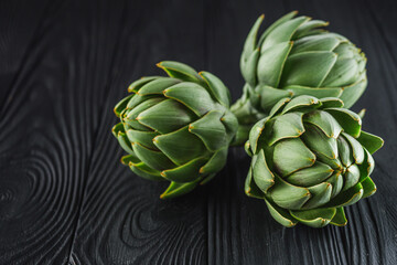 fresh natural artichokes on a black wooden background