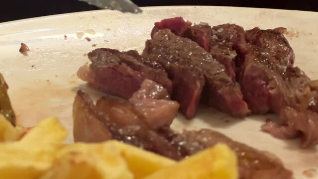Using a knife and fork to slice through tender meat pieces, showcases the concept of elegant dining etiquette and culinary refinement.