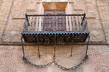 Balcony with wrought iron and chains on monumental facade