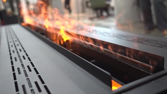 A bio-ethanol fireplace burns with orange flames in a dark room