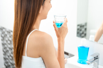 Young asian woman with mouthwash for the health of teeth in restroom. Take care and good dental health fresh breath with mouthwash.