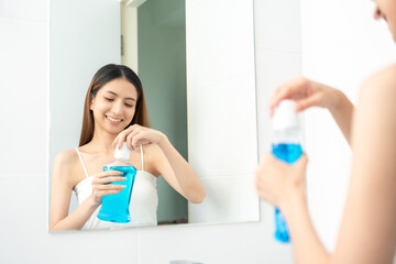 Young asian woman with mouthwash for the health of teeth in restroom. Take care and good dental health fresh breath with mouthwash.