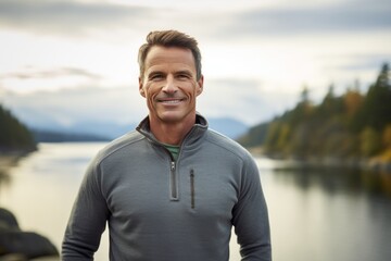 Portrait of a smiling man in his 40s dressed in a comfy fleece pullover over serene lakeside view