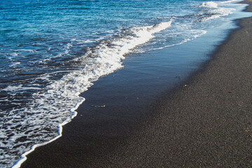 Plage de sable noir et village de Perissa, sur l'ile de Santorin, en Grèce, au mois d'avril 2024. 