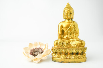 Fototapeta premium A golden statue of a Buddhist figure meditating decorate with colorful flowers facing the front isolated on white background. Concept for Vesak Day and Enlightenment Day