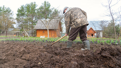 Male farmer with shovel digging earth. Preparation of the summer cottage plot, digging and fertilizing the land, Spring work in the country.