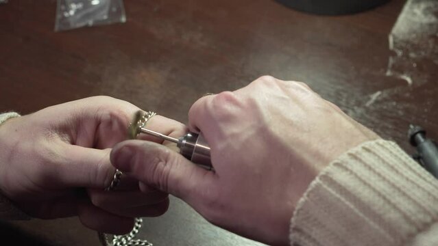 Jeweler is polishing silver chain on the polishing machine. Goldsmith working on his workshop.