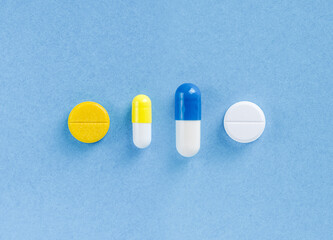 Medical capsules and pills in a line on light blue top view. Preventive medicine and healthcare
