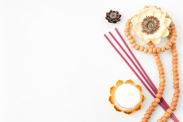Isolated Empty white background decorated with colorful flowers, red colored incense, round white candle and prayer beads. Concept for Vesak Day and Enlightenment Day. Empty blank copy text space