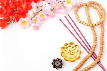 Isolated Empty white background decorated with colorful flowers, red colored incense and prayer beads. Concept for Vesak Day and Enlightenment Day. Empty blank copy text space