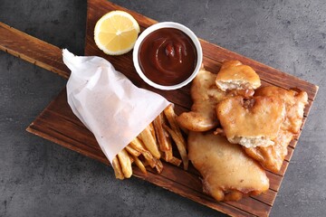 Tasty fish, chips and sauce on grey table, top view
