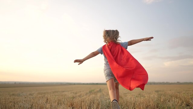 kid superhero run. girl daughter happy family a dream concept. baby girl superhero run in red cape at sunset. portrait child superhero in the park. strength fantasy lifestyle concept