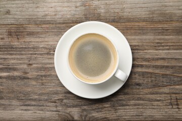 Aromatic coffee in cup on wooden table, top view