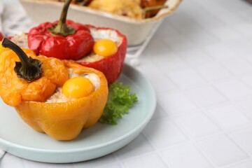 Delicious stuffed bell peppers with fried eggs on white tiled table, closeup. Space for text