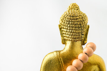 A golden statue of a Buddhist figure meditating and wearing prayer beads facing the back isolated...