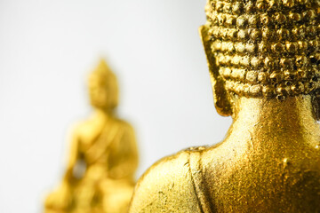 A golden statue of a Buddhist figure meditating facing the back isolated on white background....
