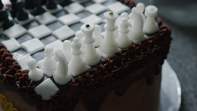 Contemporary chocolate cake with chocolate smudge, decorated with handmade marzipan chess pieces and golden words happy birthday.